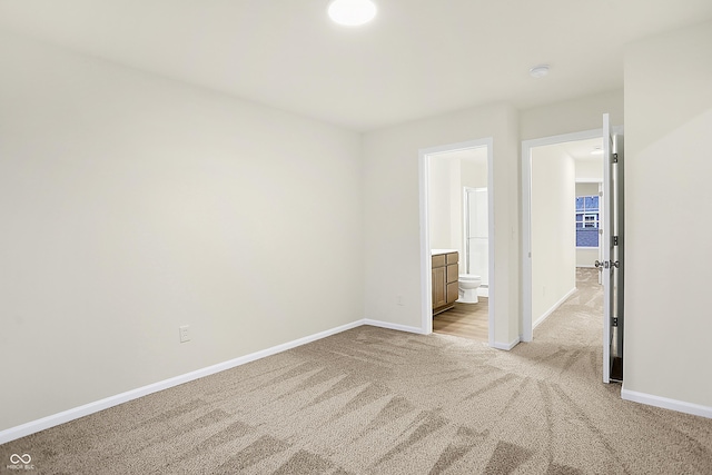 spare room featuring light colored carpet and baseboards