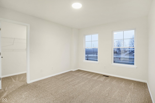 unfurnished bedroom with visible vents, a closet, carpet floors, baseboards, and a spacious closet