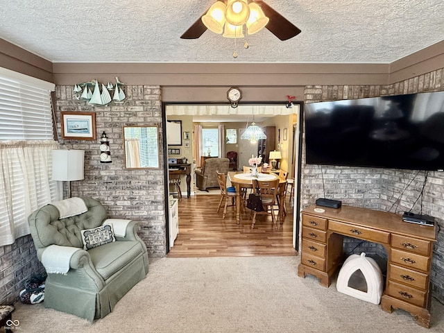 living room with a ceiling fan, a textured ceiling, and light colored carpet