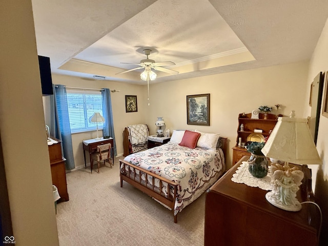 bedroom with a tray ceiling, crown molding, a ceiling fan, light carpet, and baseboards