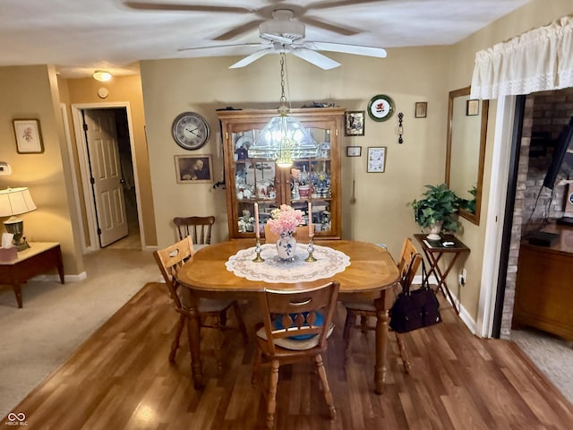 dining space with carpet floors, baseboards, a ceiling fan, and wood finished floors