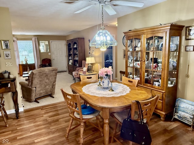 dining area featuring ceiling fan with notable chandelier, light wood-style flooring, and baseboards