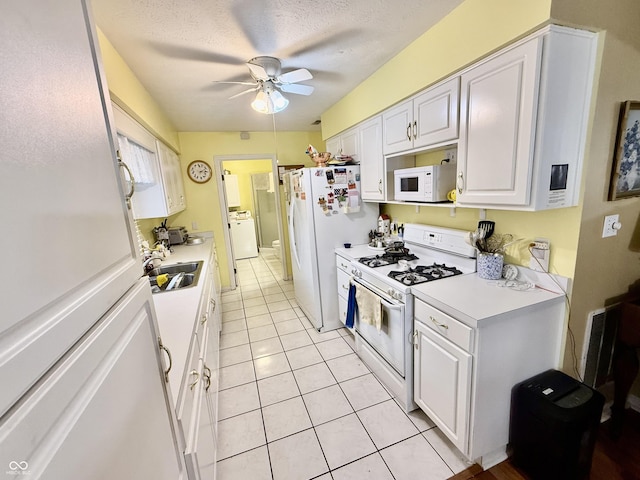 kitchen with white appliances, a sink, white cabinets, light countertops, and washer / dryer