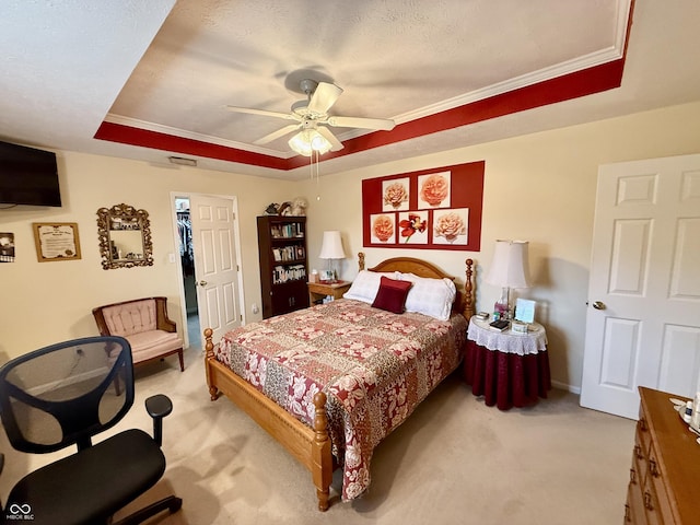 bedroom featuring a tray ceiling, light colored carpet, ceiling fan, and a textured ceiling