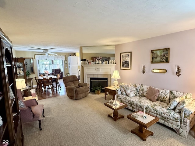 living area with carpet floors, a fireplace, and a ceiling fan