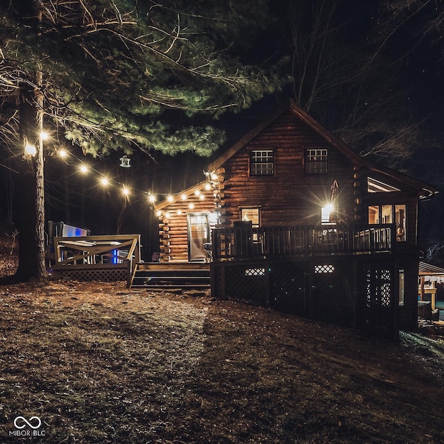 property exterior at twilight with log siding and a deck