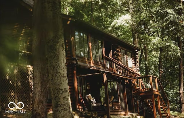 view of side of property featuring log siding, a wooden deck, and stairs