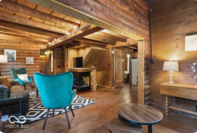 living room featuring beamed ceiling, log walls, a high ceiling, and wood finished floors