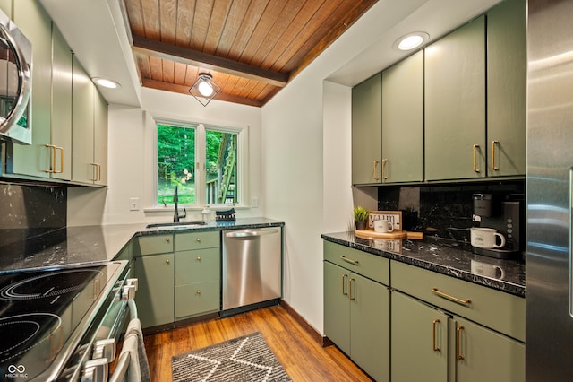 kitchen featuring tasteful backsplash, beamed ceiling, green cabinetry, appliances with stainless steel finishes, and a sink