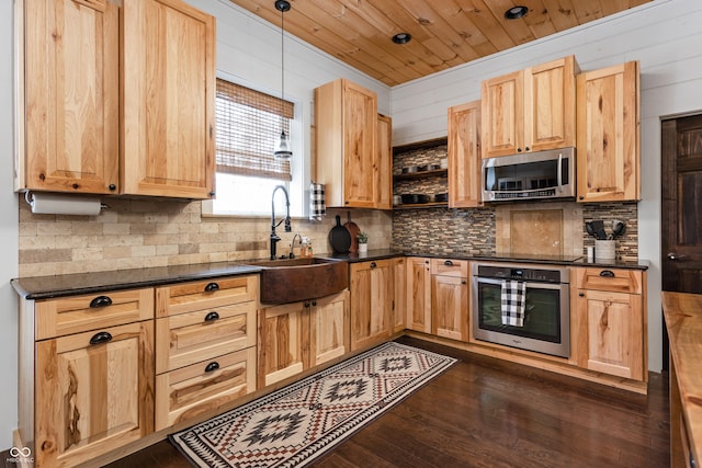 kitchen with dark countertops, light brown cabinets, appliances with stainless steel finishes, and a sink