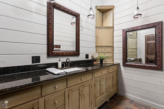 bathroom with baseboards, wood walls, and vanity