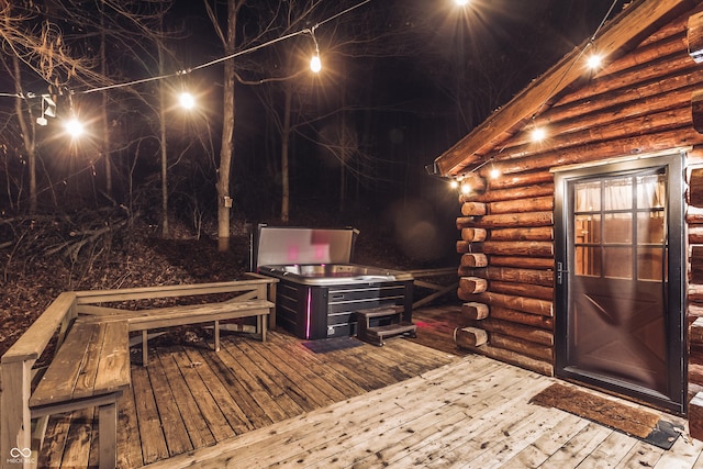 deck at night featuring a hot tub