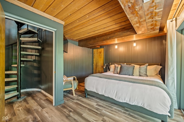 bedroom with wood walls, wooden ceiling, baseboards, and wood finished floors