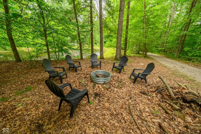 surrounding community featuring a fire pit and a wooded view