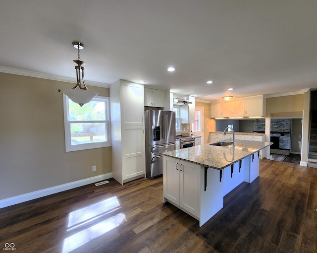 kitchen featuring light stone counters, appliances with stainless steel finishes, ornamental molding, white cabinets, and a sink