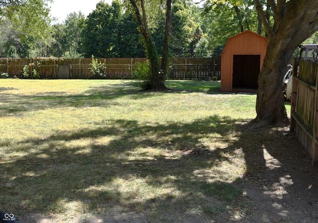 view of yard with a fenced backyard, an outdoor structure, and a storage unit