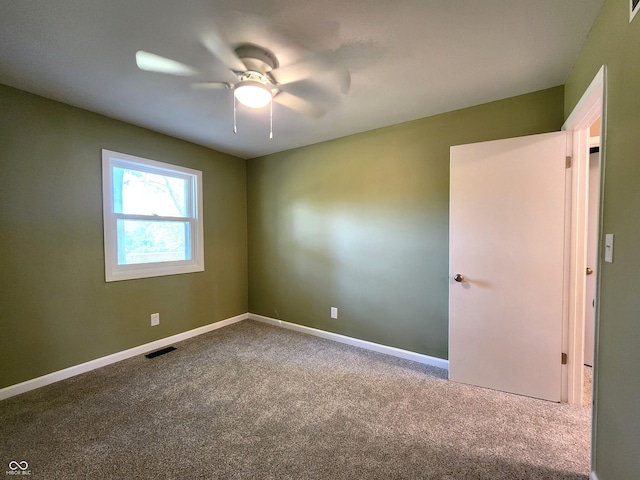 carpeted empty room with ceiling fan, visible vents, and baseboards