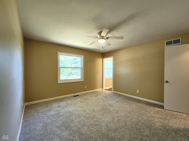 carpeted spare room with visible vents, ceiling fan, and baseboards