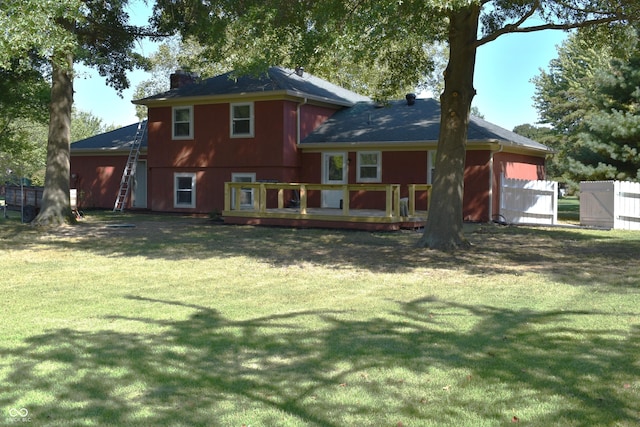 back of house featuring a deck, a lawn, a chimney, and fence