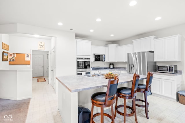936 Plunkett Ave, Westfield, IN 46074 - kitchen featuring appliances with stainless steel finishes, recessed lighting, light countertops, a kitchen island with sink, and a kitchen breakfast bar