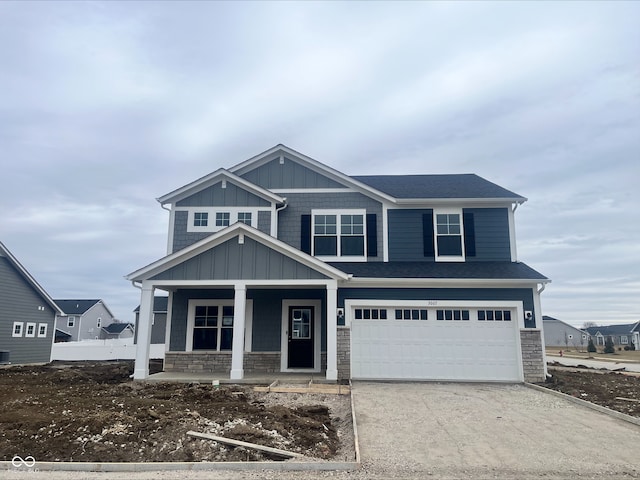 view of front facade featuring stone siding, a porch, concrete driveway, and an attached garage