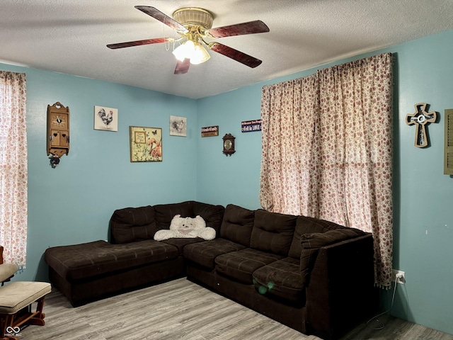 living room featuring a ceiling fan, a textured ceiling, and wood finished floors