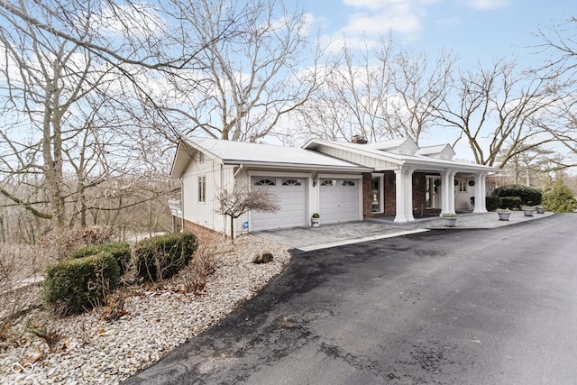 exterior space featuring aphalt driveway, an attached garage, and a chimney