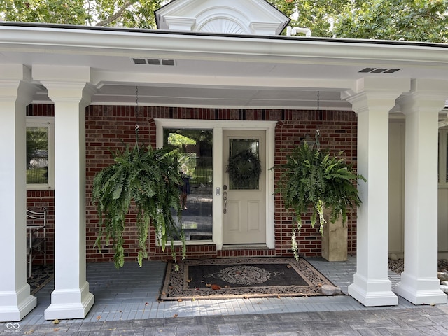 doorway to property with brick siding and covered porch