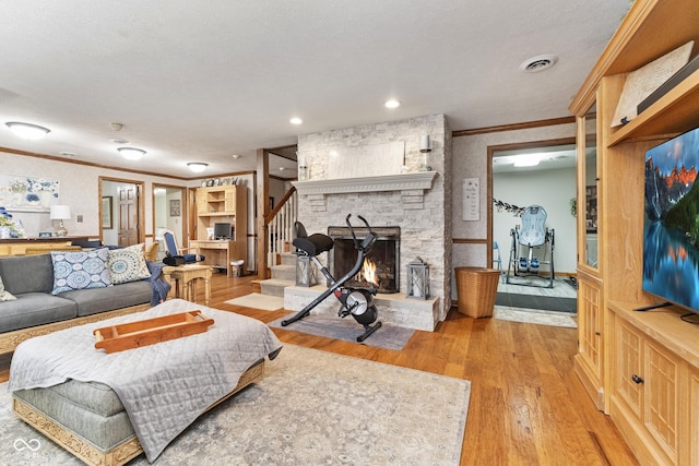 living room with light wood-type flooring, visible vents, ornamental molding, stairway, and a fireplace