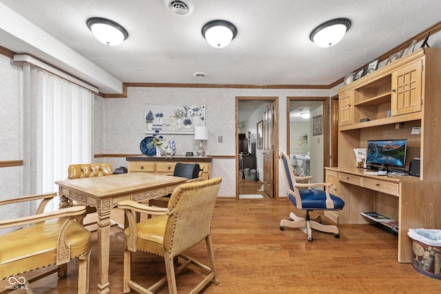 dining space with visible vents, wallpapered walls, built in study area, and light wood-style floors