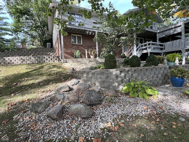 back of house featuring stairway, brick siding, and a balcony