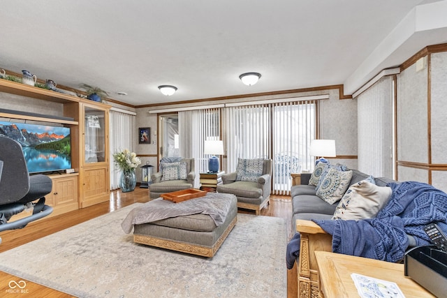 living area featuring wood finished floors, crown molding, and wallpapered walls