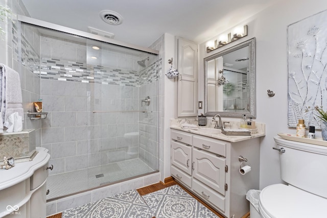 bathroom featuring visible vents, toilet, a stall shower, and vanity