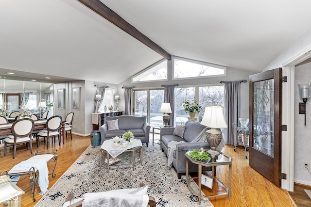 living room featuring a healthy amount of sunlight, lofted ceiling with beams, baseboards, and wood finished floors