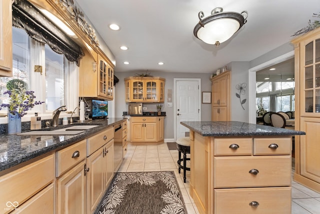 kitchen with light brown cabinetry, a sink, a kitchen island, a breakfast bar area, and light tile patterned floors