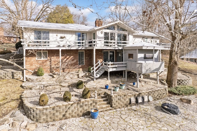 rear view of property featuring a wooden deck, brick siding, a chimney, and stairway