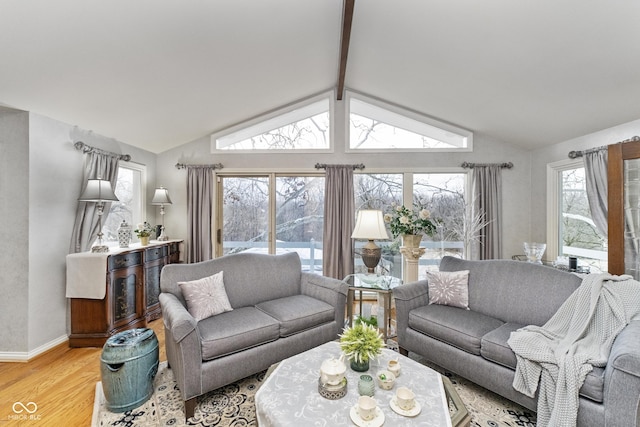 living area featuring light wood-style flooring, vaulted ceiling with beams, and baseboards