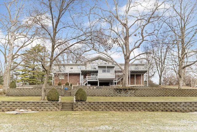 back of house with brick siding, stairway, a yard, and a sunroom