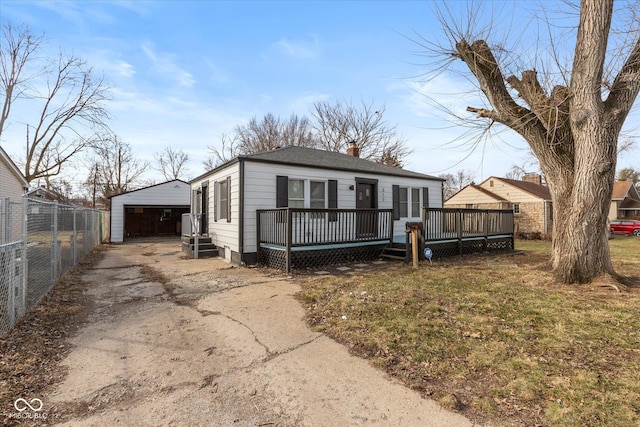 view of front of home featuring an outbuilding, a detached garage, a chimney, fence, and a deck