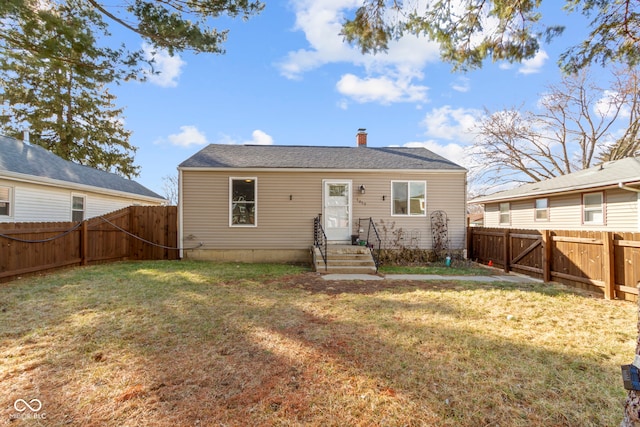 rear view of property featuring a fenced backyard, a yard, and a chimney