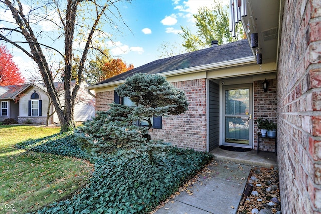 property entrance featuring a yard and brick siding