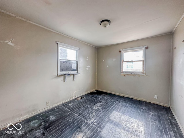 empty room featuring baseboards, hardwood / wood-style floors, and crown molding