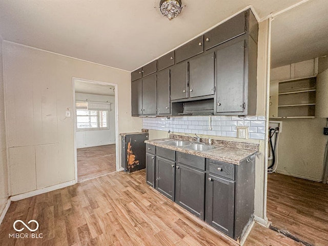 kitchen with light wood-type flooring, light countertops, a sink, and decorative backsplash