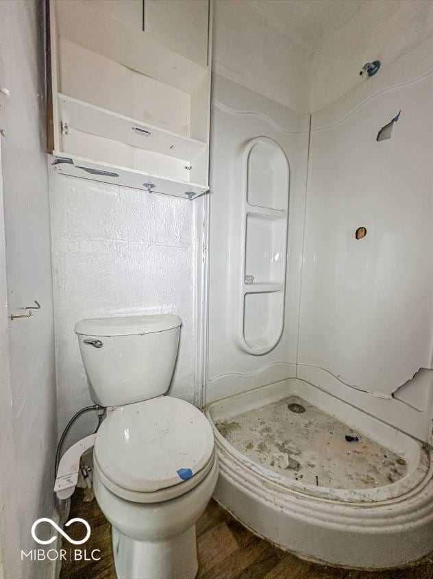 full bath featuring wood finished floors, a shower stall, and toilet