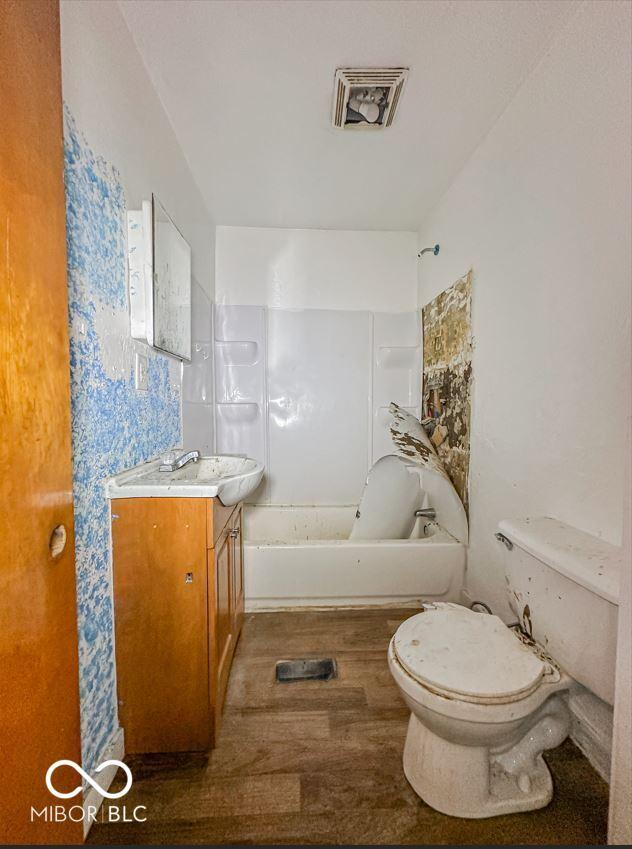 bathroom featuring shower / washtub combination, visible vents, toilet, vanity, and wood finished floors