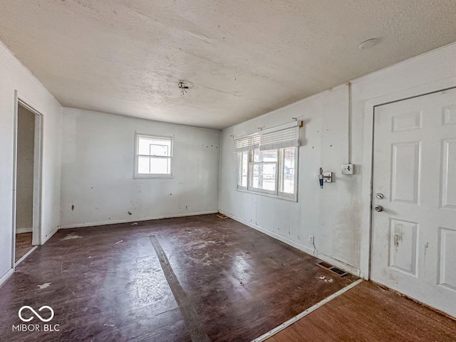 foyer entrance with a textured ceiling, visible vents, and baseboards