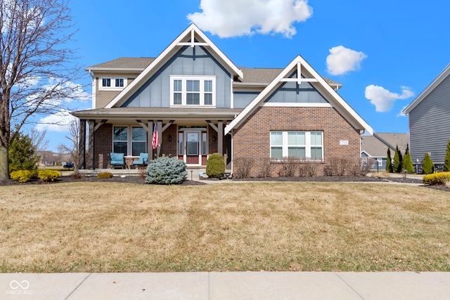 view of front of home featuring a porch, brick siding, board and batten siding, and a front lawn