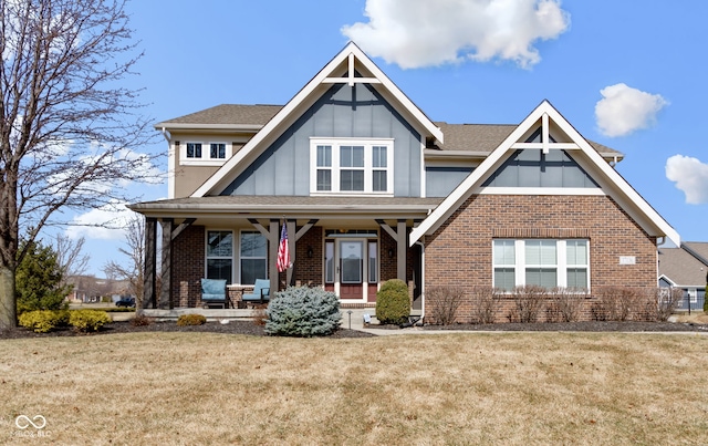 view of front of property with a porch, brick siding, a shingled roof, a front lawn, and board and batten siding