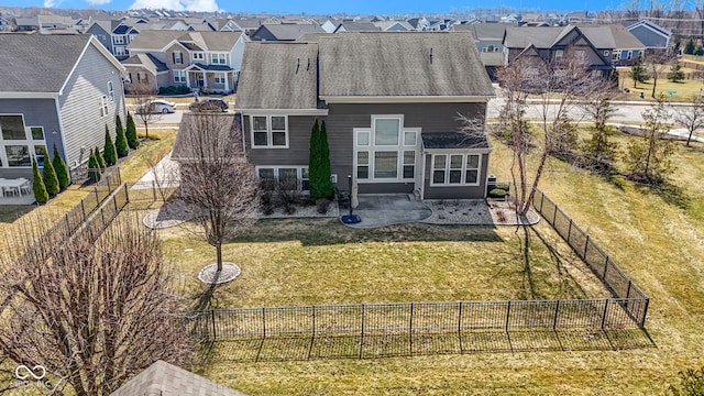 back of house with a fenced backyard, a residential view, and a lawn