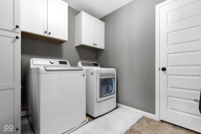 laundry room with washing machine and dryer, cabinet space, and baseboards